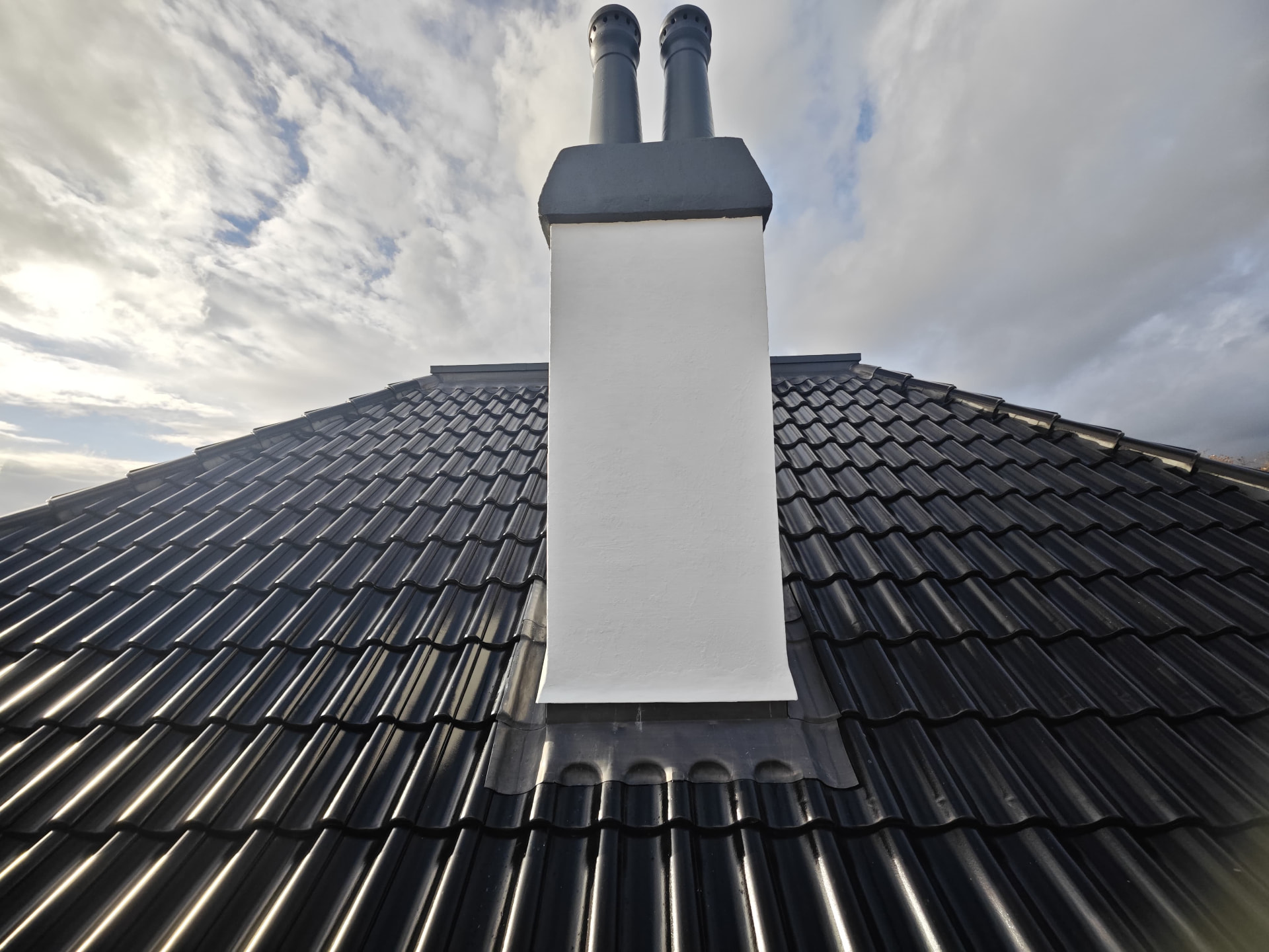Glazed black pan tile roof with rendered chimney and lead flashing