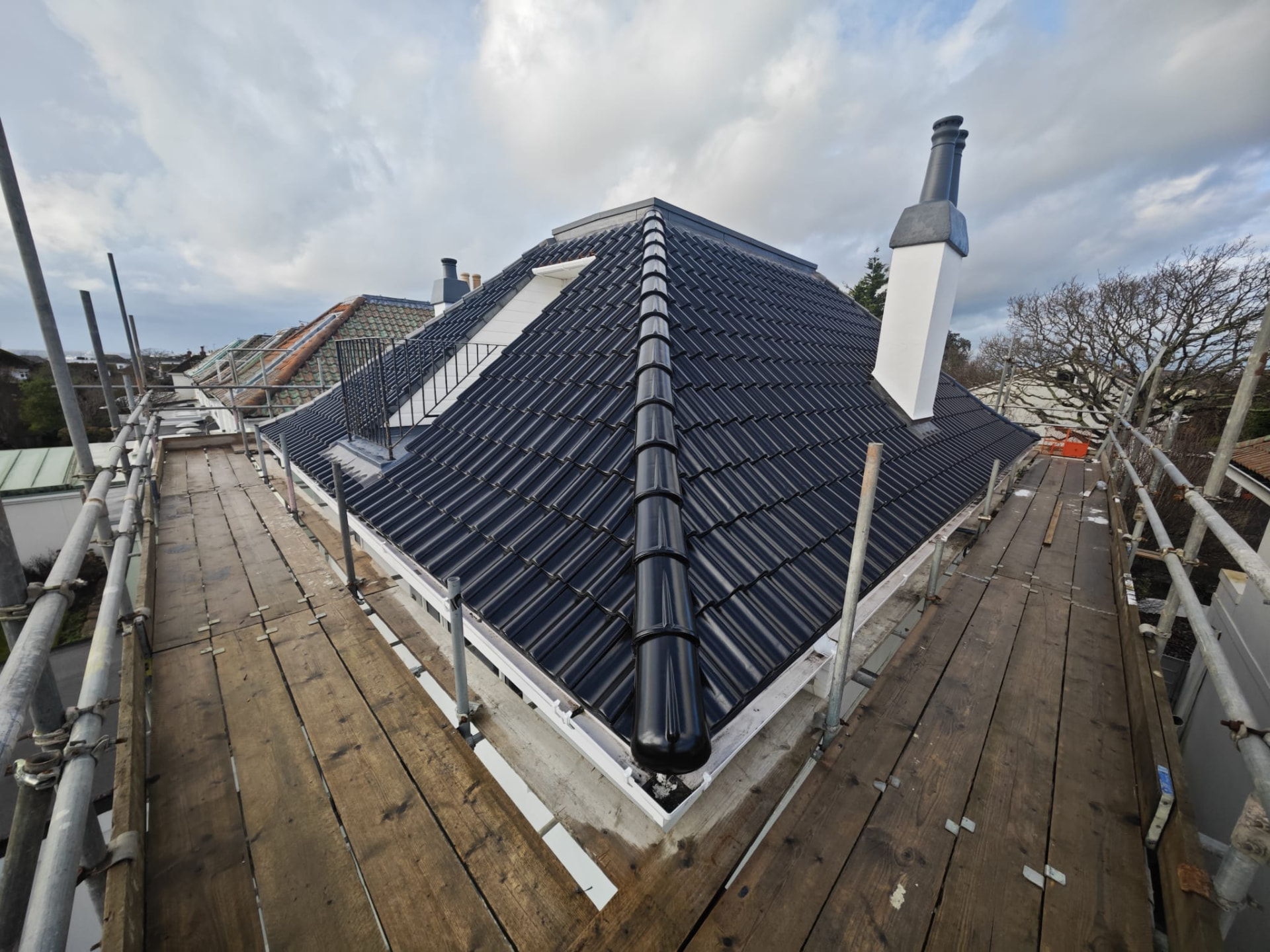 Glazed black pan tile hipped roof under scaffold