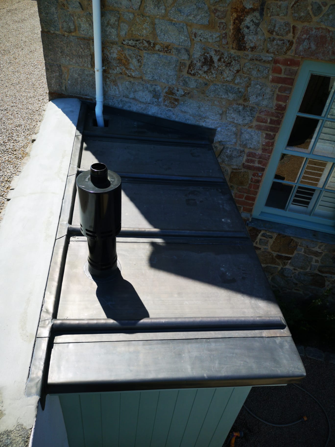 Lead flat roof against granite wall with flue and rolls