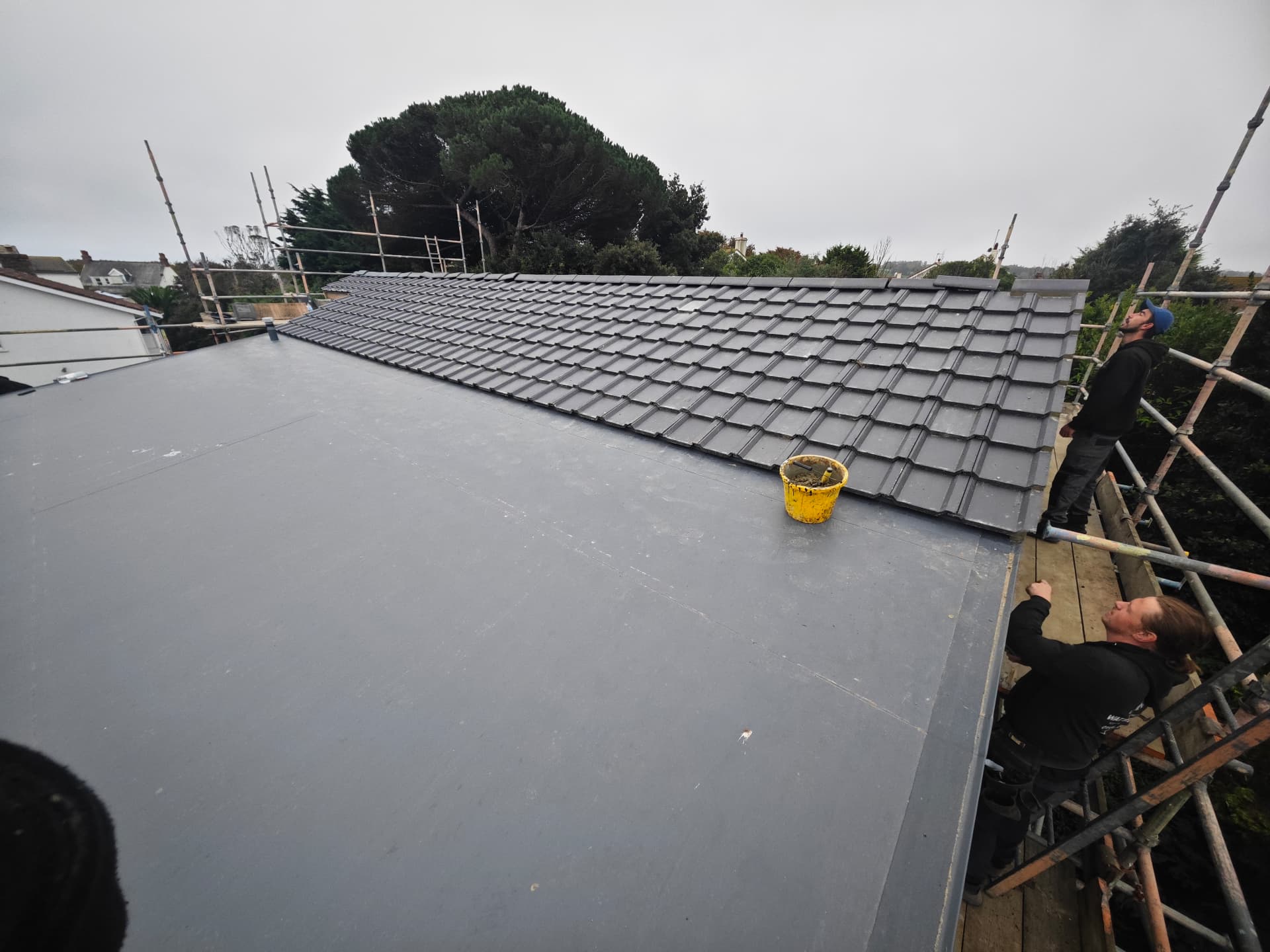 New build tiled roof beside a finished flat roof section, Kampong