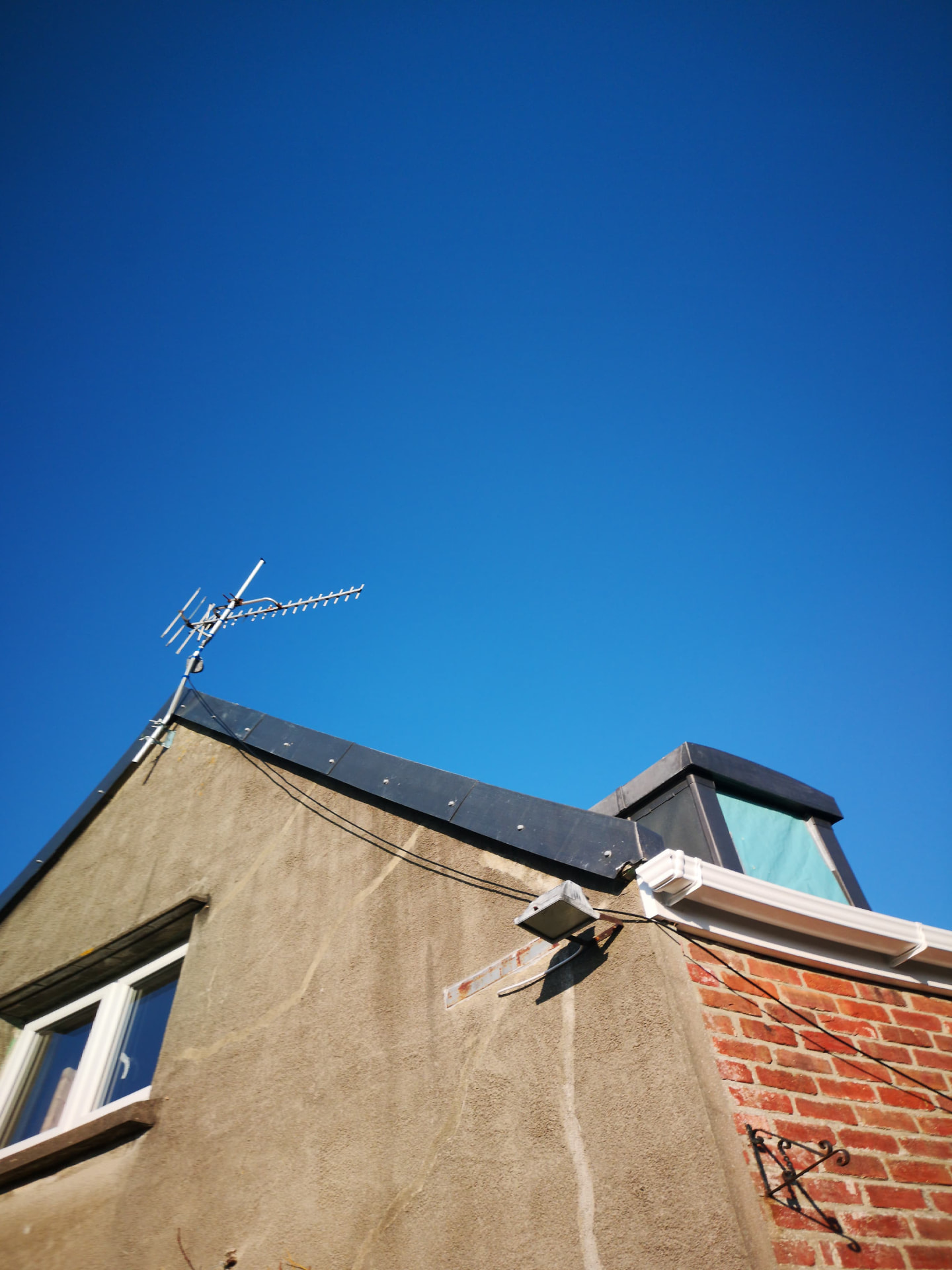 Lead-clad dormer and ridge detail against blue sky, Coin Gervais
