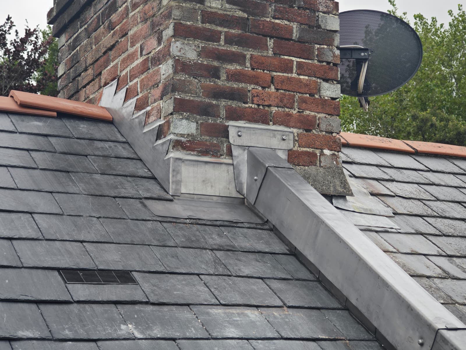 Lead step flashing and back gutter to a brick chimney on a slate roof, L'Enclos Cottages