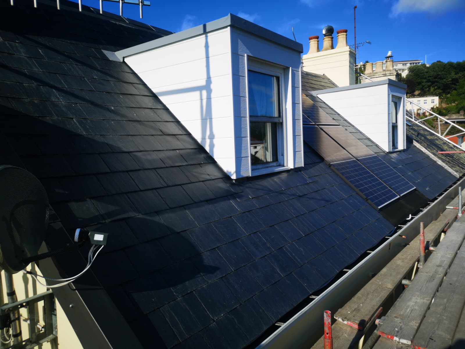 Reroofed slate slopes with white timber dormers and solar panels, Brookvale