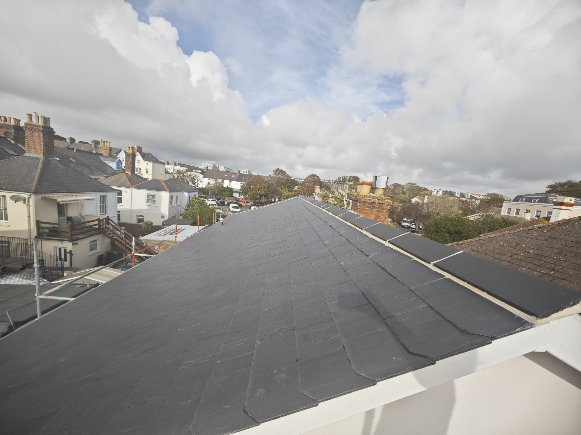 Long slate roof slope with lead ridge across town rooftops, L'Abri