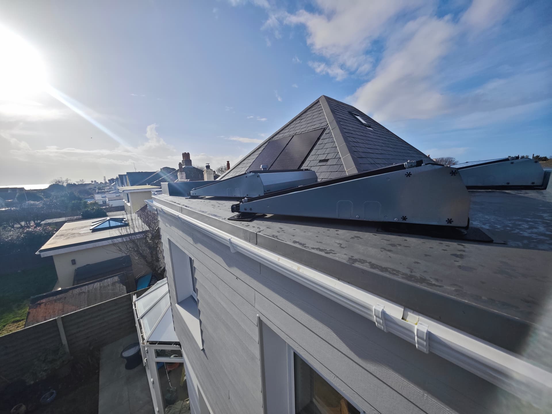 Warm flat roof and solar mounting frames beside a Spanish slate hip, Le Clos