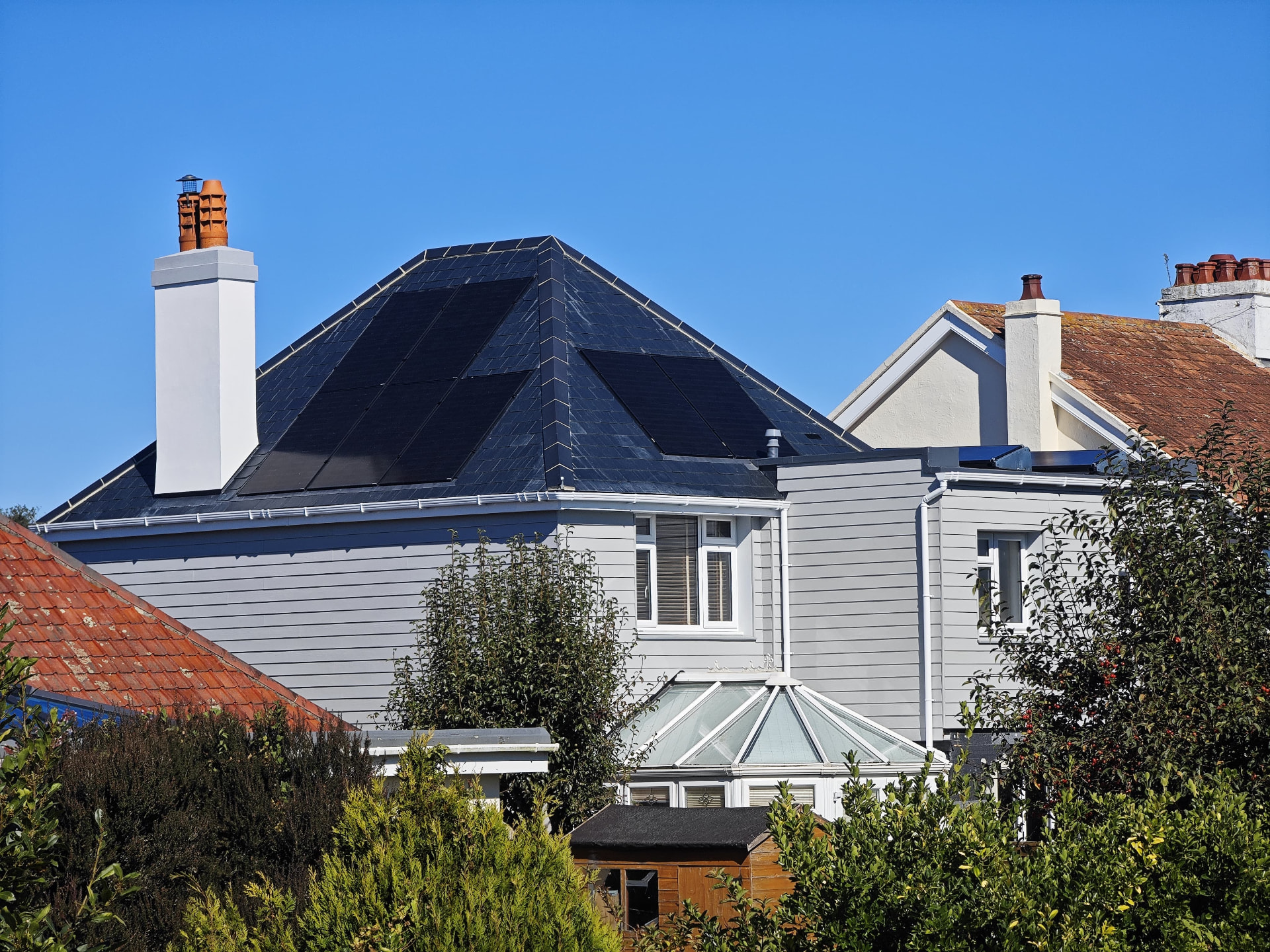 Finished Spanish slate roof with PV solar array and HardiPlank cladding, Le Clos