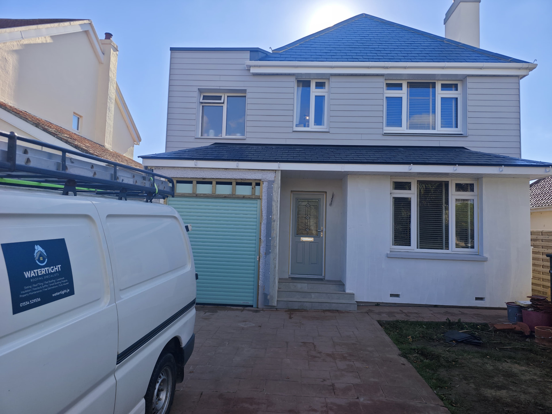 Front elevation of a refurbished house with slate lean-to and HardiPlank cladding, Le Clos