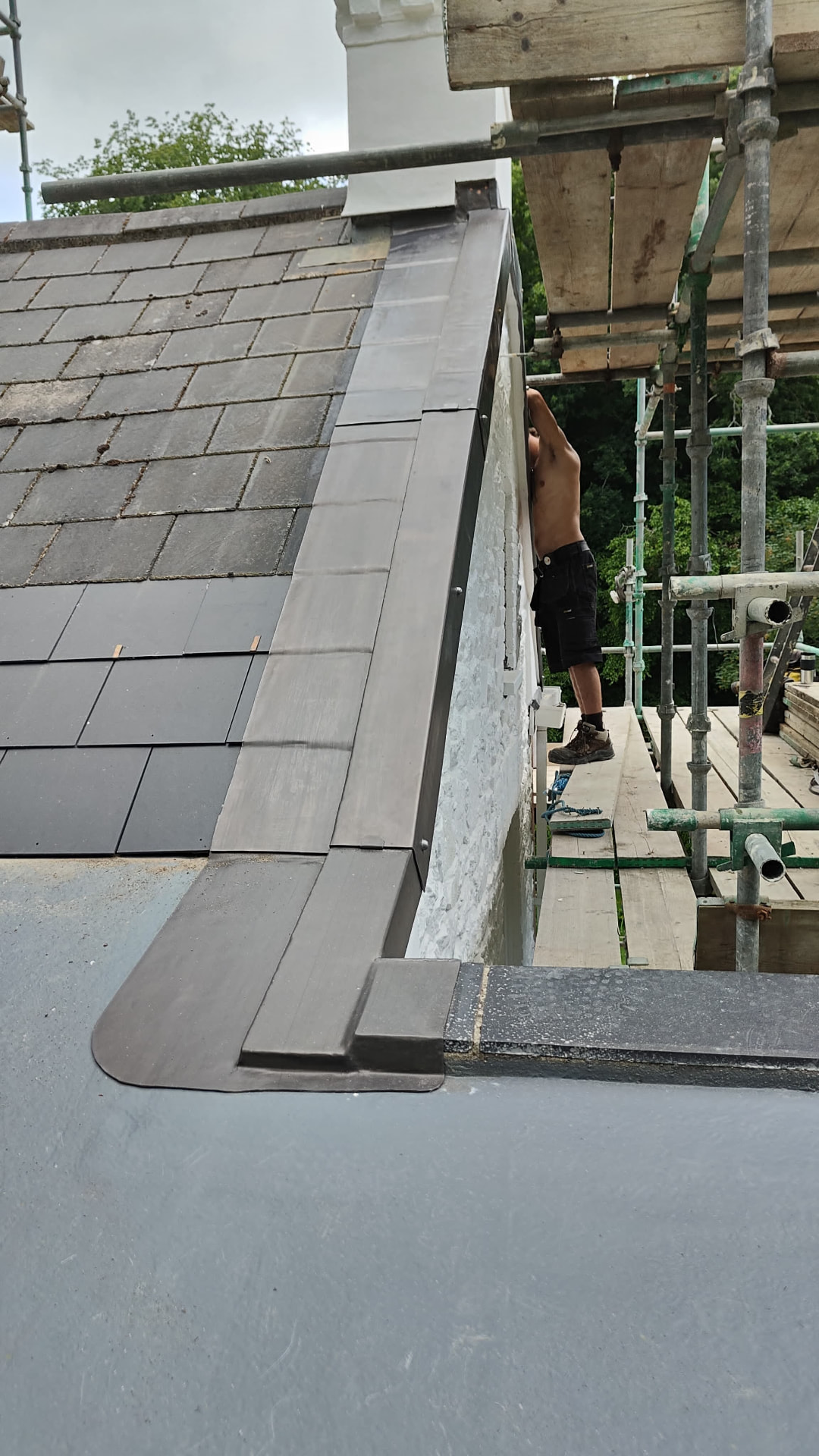 Lead capping run along a Jersey verge with slate roof and scaffold, Grande Vaux