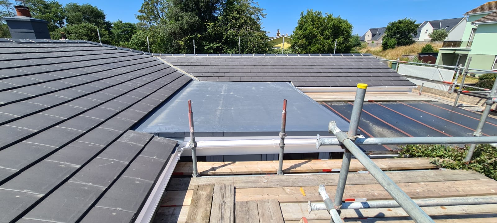 Tiled slopes meeting a single-ply flat roof with new guttering, Clos de Patier