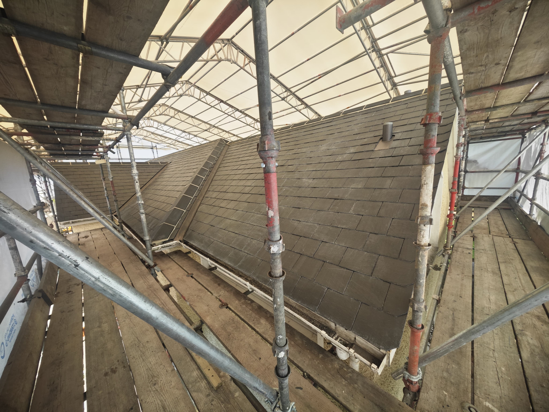 Slate roof being relaid under a temporary scaffold roof, Petite Menage