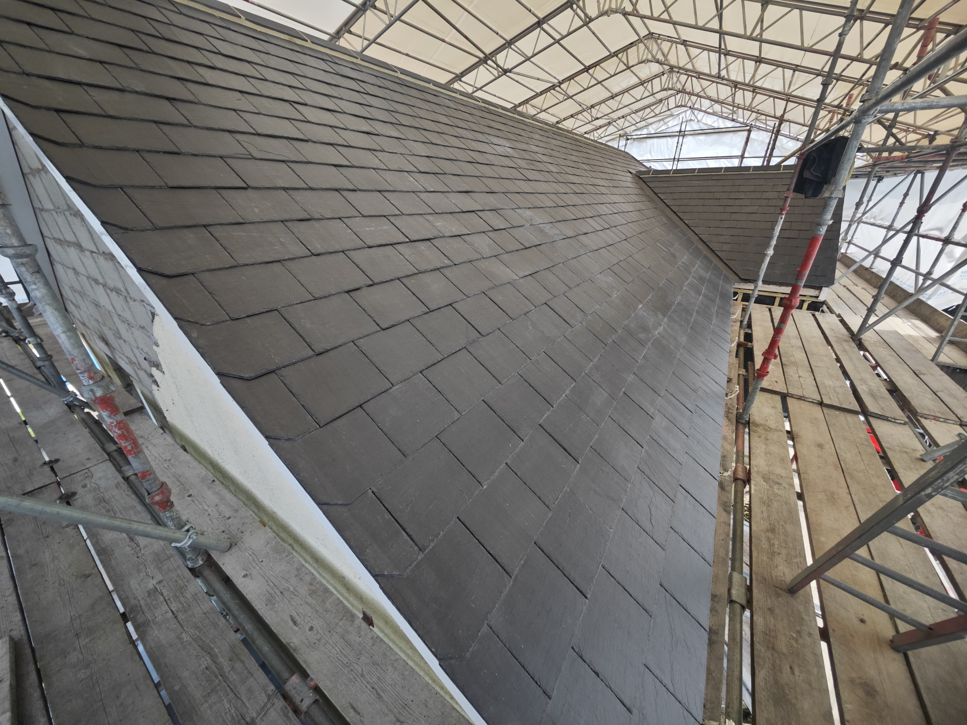 Long hipped slate roof completed under scaffold sheeting, Petite Menage