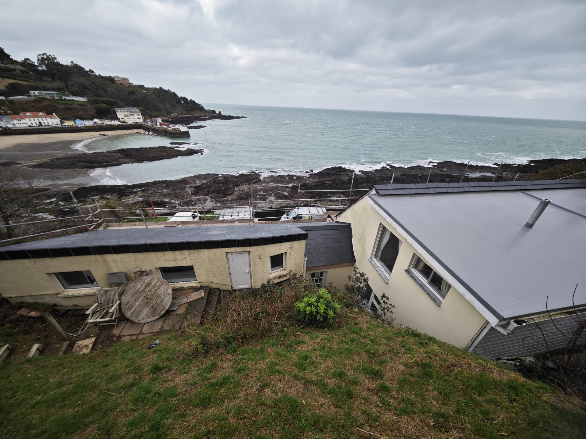 Reroofed slate and membrane roofs above a Jersey bay, Rivage de la Mer